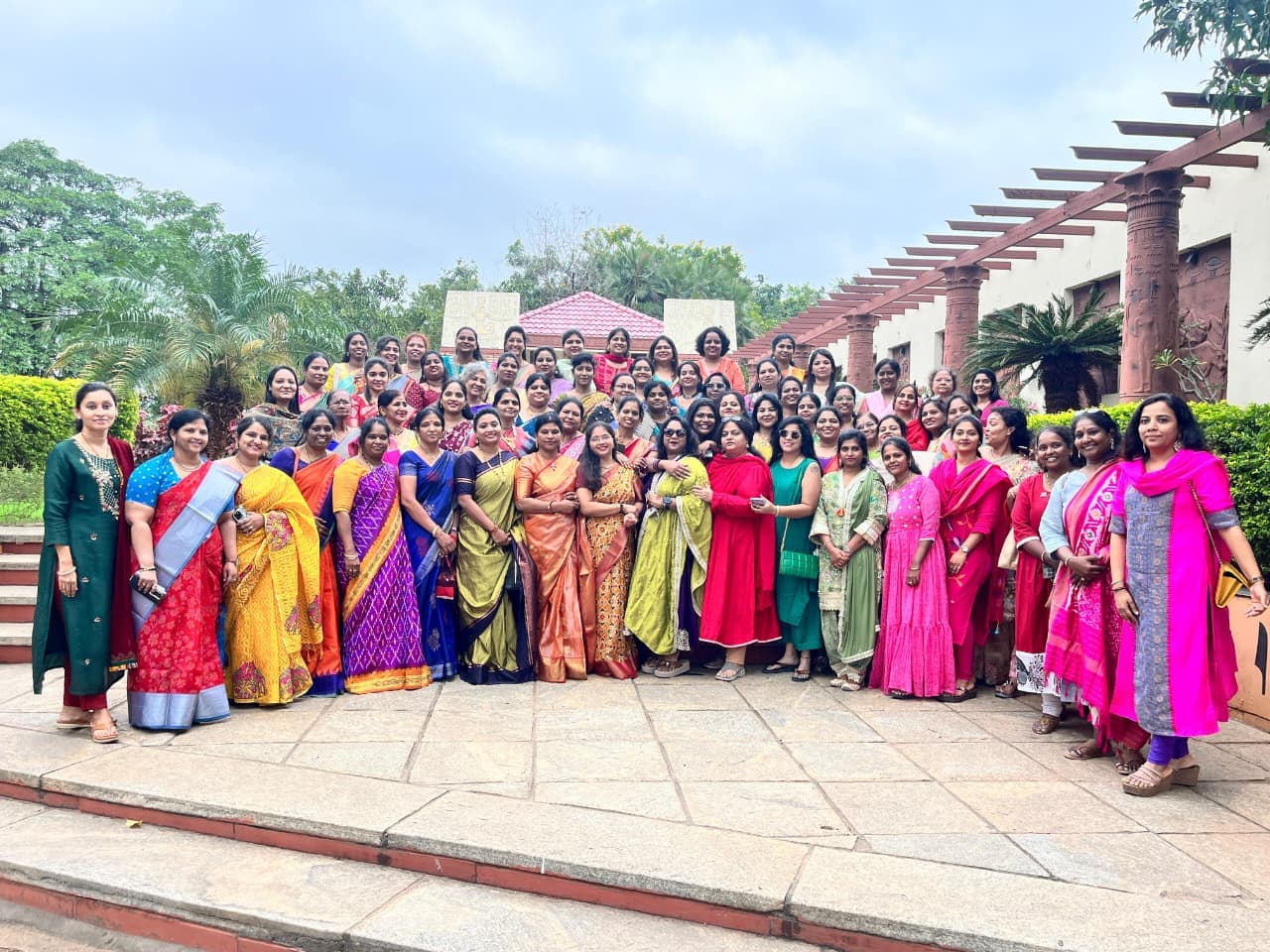 Members of the DEWI collective standing together outdoors on a stone terrace at a resort, on a bright day.
